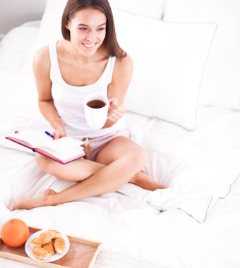 Yatakta oturmuş ve bir defterini yazma genç güzel kadın