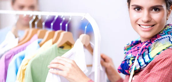 Beautiful young stylist woman near rack with hangers — Stock Photo, Image