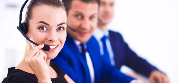 Retrato de mulher de negócios bonita em fones de ouvido sorrindo com colegas de fundo — Fotografia de Stock