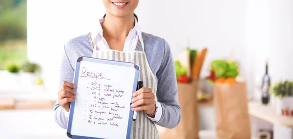 Kvinna i köket hemma, stående nära skrivbord med mapp — Stockfoto