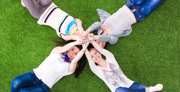 四名年轻女子躺在绿色的草地上 — 图库照片