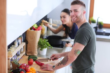 Bir çift evdeki mutfaklarında birlikte yemek pişiriyor.