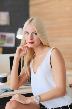 Moda tasarımcıları stüdyoda çalışıyor. Masanın üzerinde oturuyorlar..