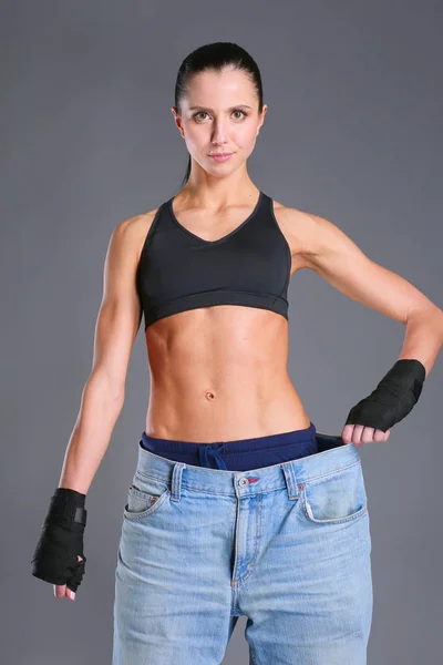 Junge Fitness-Frau zeigt, dass ihre alten Jeans . — Stockfoto