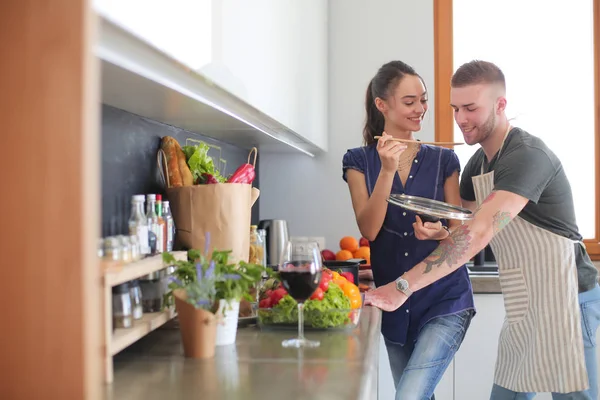 Bir çift evdeki mutfaklarında birlikte yemek pişiriyor.