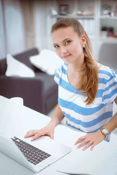 Žena s dokumenty sedí na stole s notebookem — Stock fotografie