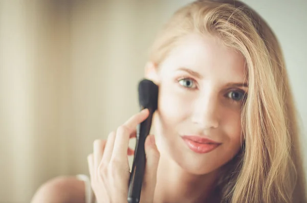 Mulher bonita aplicando maquiagem com escova — Fotografia de Stock