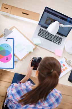 Dizüstü bilgisayar ile masaya oturan kadın fotoğrafçı. Kadın fotoğrafçı