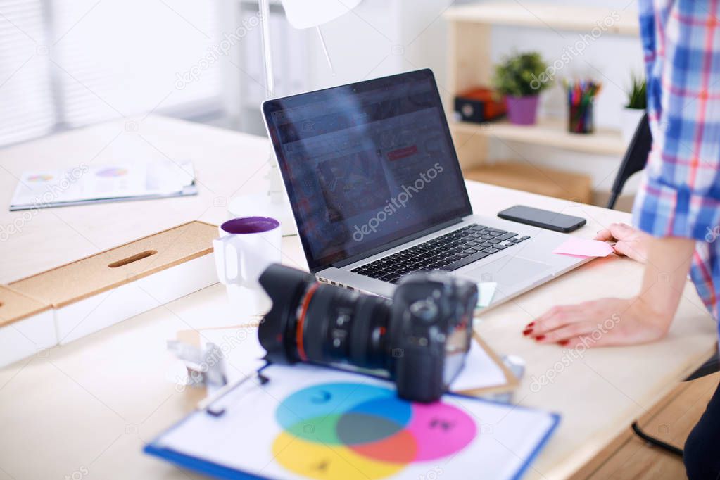 Female photographer sitting on the desk with laptop . Female photographer
