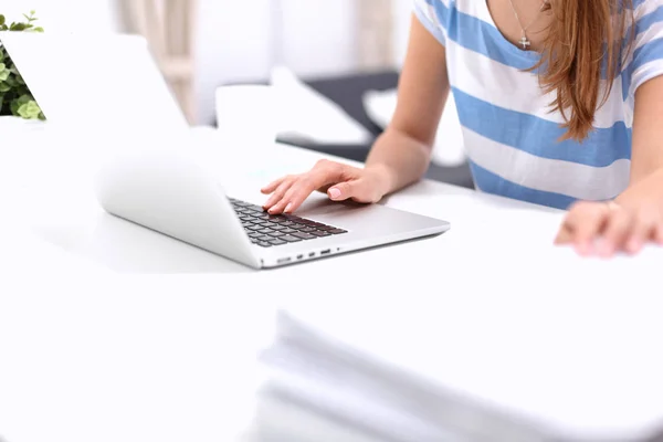 Kvinde med dokumenter siddende på skrivebordet med laptop - Stock-foto