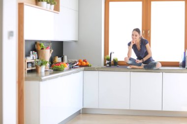 Lotus pozisyonunda mutfak masasında oturan genç güzel kadın