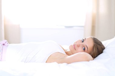 Yatakta rahat ve mutlu bir şekilde yatan güzel bir genç kadın..