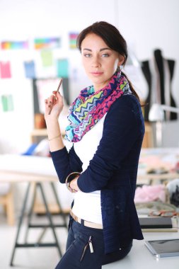 Güzel moda tasarımcısı stüdyoda duruyor. .