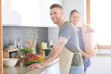 Bir çift evdeki mutfaklarında birlikte yemek pişiriyor.