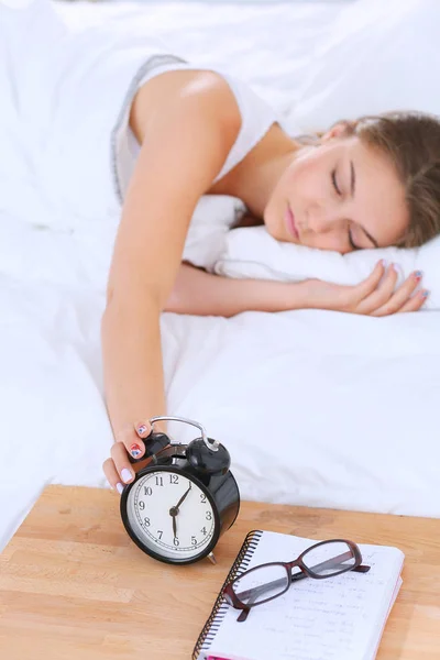 Una mujer joven apagando su despertador por la mañana. — Foto de Stock