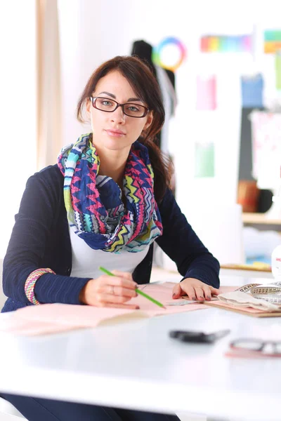 Mooie modeontwerper zit aan het bureau in studio . — Stockfoto