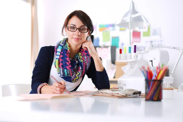 Hermoso diseñador de moda sentado en el escritorio en el estudio . —  Fotos de Stock