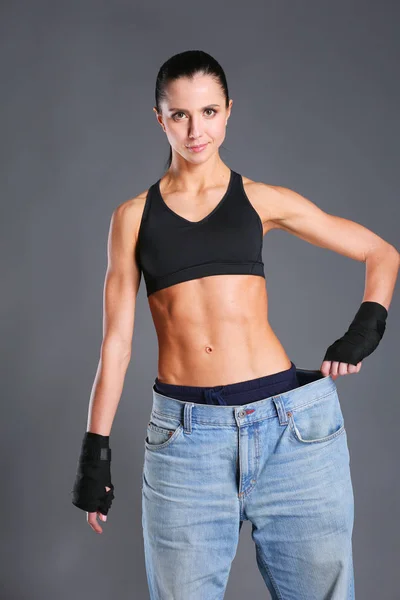 Junge Fitness-Frau zeigt, dass ihre alten Jeans . — Stockfoto