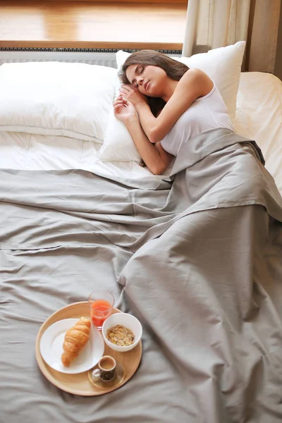 Молодая женщина сидит в постели с чашкой молока — стоковое фото