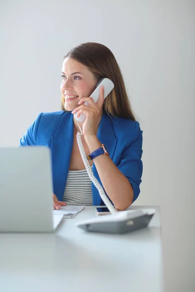 Portret van een jonge vrouw op telefoon achter een laptopcomputer — Stockfoto