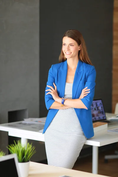 Портрет красивой деловой женщины, стоящей рядом с рабочим местом. — стоковое фото