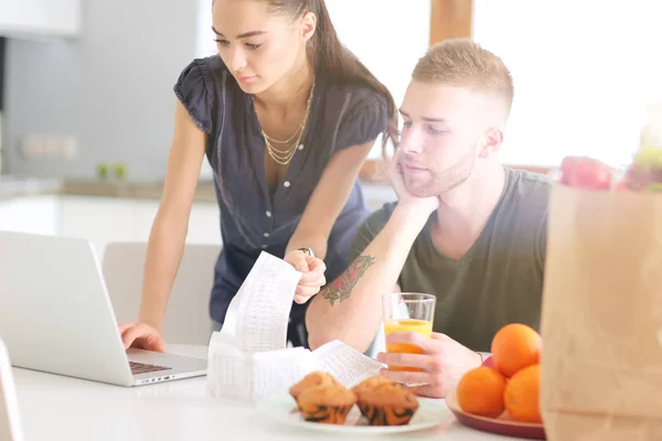 Paret betalar sina räkningar med laptop i köket hemma — Stockfoto