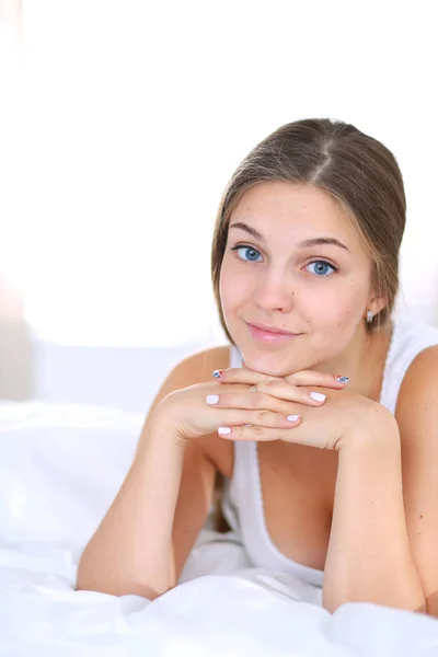 Uma bela jovem deitada na cama confortavelmente e alegremente. — Fotografia de Stock