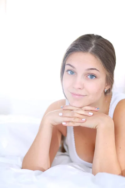 Uma bela jovem deitada na cama confortavelmente e alegremente. — Fotografia de Stock