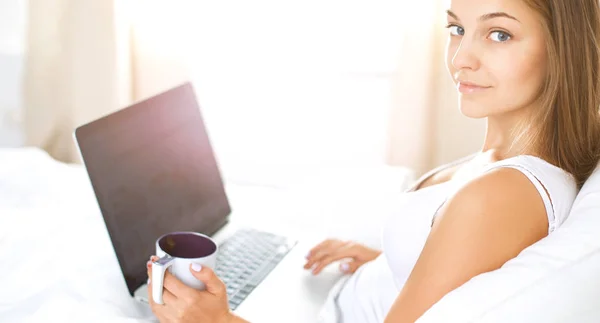 Bella giovane donna con computer portatile a letto e godersi una tazza di tè — Foto Stock