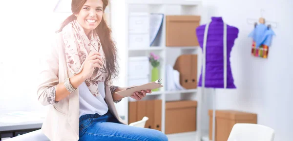 Smiling female fashion designer sitting at office desk — Stock Photo, Image