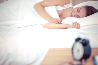 Yatakta rahat ve mutlu bir şekilde yatan güzel bir genç kadın..