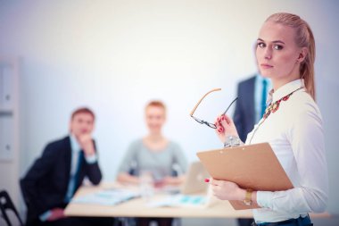 Ofiste çalışan genç bir kadının portresi klasörle duruyor. Genç bir kadının portresi. İş kadını