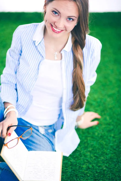 Jonge vrouw zit met boek op gras. Jonge vrouw — Stockfoto