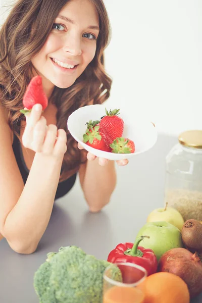 Flicka sitter i köket på skrivbord med frukt och glas med juice. — Stockfoto