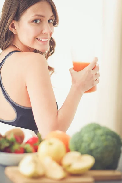 Flicka sitter i köket på skrivbord med frukt och glas med juice. — Stockfoto