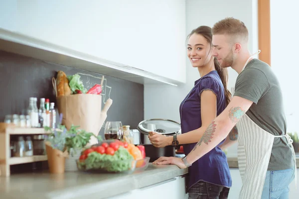 Bir çift evdeki mutfaklarında birlikte yemek pişiriyor.