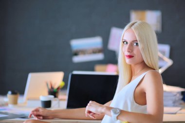 Moda tasarımcıları stüdyoda çalışıyor. Masanın üzerinde oturuyorlar.