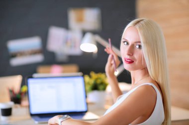 Moda tasarımcıları stüdyoda çalışıyor. Masanın üzerinde oturuyorlar.