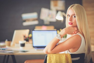 Moda tasarımcıları stüdyoda çalışıyor. Masanın üzerinde oturuyorlar.