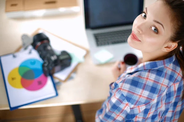 Masada dizüstü bilgisayarla oturan kadın fotoğrafçı.