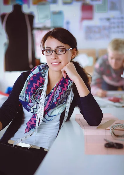 Beautiful fashion designer sitting at the desk in studio — Stock Photo, Image