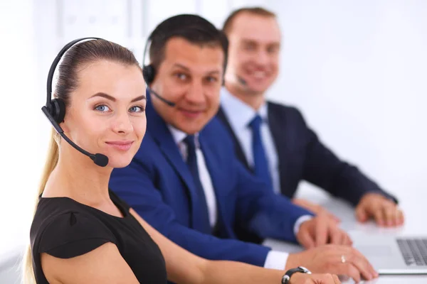 Portret van prachtige zakenvrouw in hoofdtelefoon lachend met collega's op achtergrond. — Stockfoto