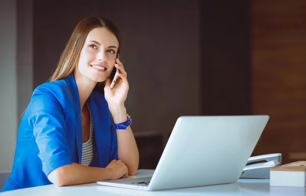 Portret van een jonge vrouw op telefoon achter een laptopcomputer — Stockfoto