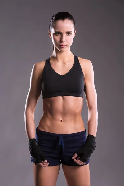 Muscular young woman posing in sportswear against black background — Stock Photo, Image