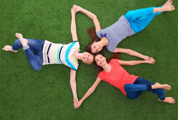 Jonge smilling vrouwen liggend op groen gras — Stockfoto