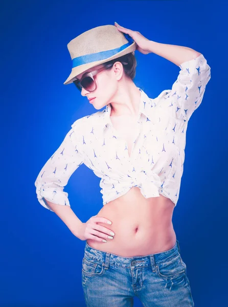 Retrato de hermoso modelo en sombrero con gafas, aislado sobre fondo azul — Foto de Stock