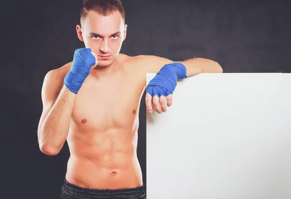 Junger gutaussehender Boxer, der in der Nähe von Bord steht, isoliert auf schwarzem Hintergrund — Stockfoto