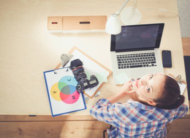 Dizüstü bilgisayar ile masaya oturan kadın fotoğrafçı. Kadın fotoğrafçı