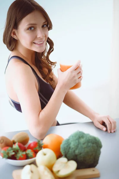 Menina sentada na cozinha na mesa com frutas e óculos com suco . — Fotografia de Stock