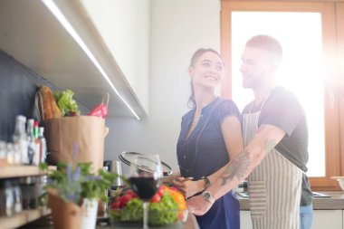 Bir çift evdeki mutfaklarında birlikte yemek pişiriyor.